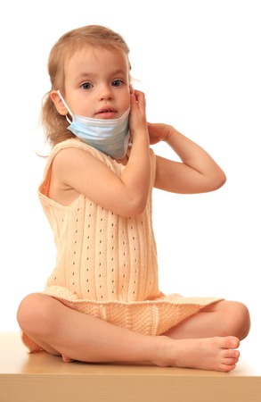 A little girl puts on a non-permanent medical mask.の写真素材