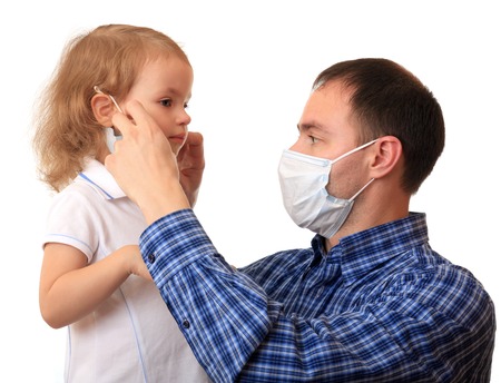 A dad puts a non-permanent medical mask on to daughter.の写真素材