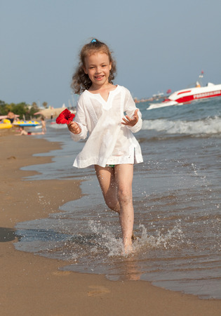 Little girl running down the summer beach.の写真素材