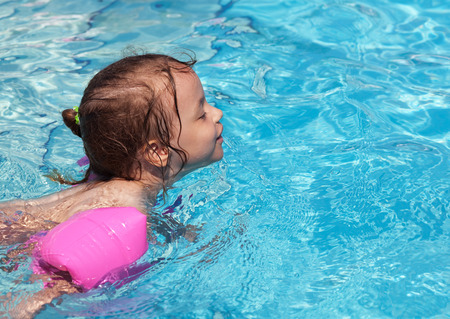 Joyful little girl swimming in the pool.の写真素材