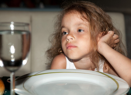 Tired hungry child in the night restaurant.の写真素材