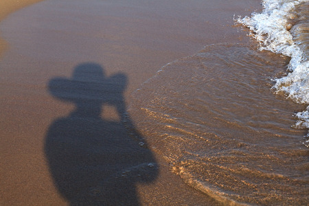 Shadow of man in hat on the sandy beach.の写真素材