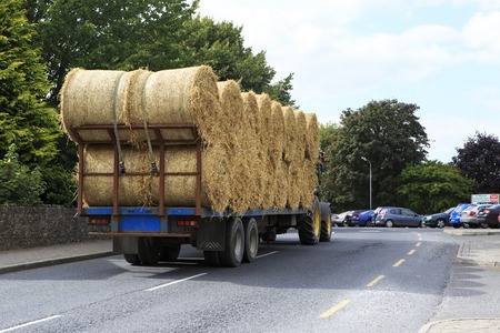 Kilkenny, Ireland - August 23, 2014: Tractor transporting straw bales in irish countrysideのeditorial素材