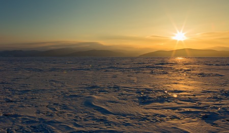 Rays of rising sun light up the snow covered ice. Beautiful winter landscape in the Lake Baikal.の写真素材