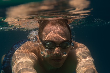 Tourist man in swimming sports glasses swimming underwater in the Aegean Sea on the coast of the...