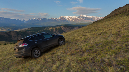 Altai Krai, Russia - July 15, 2015: Crossover Nissan X-TRAIL on the hillside in the Kurai steppe against the backdrop of the North Chuy ridge at dawn.のeditorial素材