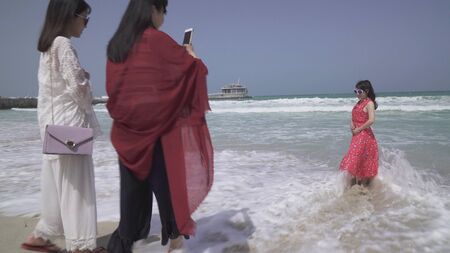 Dubai, UAE - April 01, 2018: Tourists are photographed on the background of the Persian Gulf on the Public Jumeirah Open Beach, Dubaiのeditorial素材