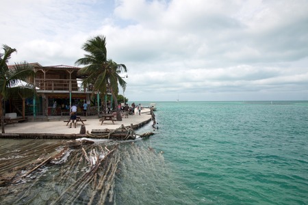 CAYE CAULKER, BELIZE - FEBRUARY 16, 2013  People leazing and drinking on the sunset in the  split of...