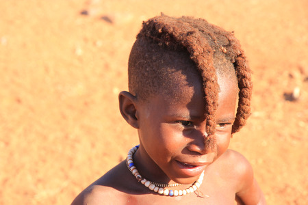 EPUPA, NAMIBIA- MAY 12, 2014: Unidentified child Himba tribe. Himba children show their traditional clothing, jewelry and headdress. The age and social status of a Himba can be seen in their hairstyle and jewelry.のeditorial素材