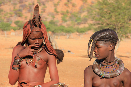 EPUPA, NAMIBIA- MAY 12, 2014: Portrait of two unidentified Himba  young woman with two children The Himba are indigenous peoples living in northern Namibia, in the Kunene region of South-West Africaのeditorial素材