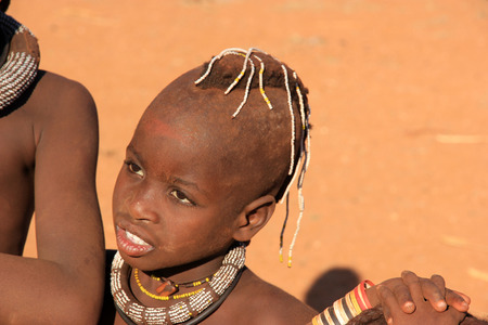 EPUPA, NAMIBIA- MAY 12, 2014: Unidentified child Himba tribe. Himba children show their traditional clothing, jewelry and headdress. The age and social status of a Himba can be seen in their hairstyle and jewelry.のeditorial素材