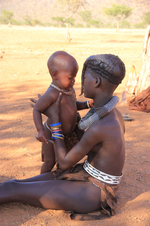 EPUPA, NAMIBIA- MAY 12, 2014: Portrait of an unidentified Himba young girl   with a children The Himba are indigenous peoples living in northern Namibia, in the Kunene region of South-West Africaのeditorial素材