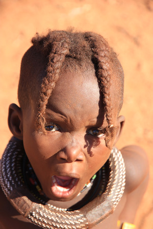 EPUPA, NAMIBIA- MAY 12, 2014: Unidentified child Himba tribe. Himba children show their traditional clothing, jewelry and headdress. The age and social status of a Himba can be seen in their hairstyle and jewelry.のeditorial素材