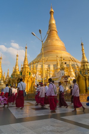 YANGON, MYANMAR - NOVEMBER 26, 2016: Ordination ceremony at the sunset in the Shwedagon pagoda with monks walking around the pagoda and carrying sacred itemsのeditorial素材