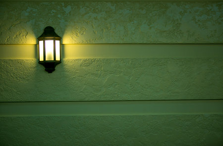 A wall-mounted bedside lamp turns dim yellow