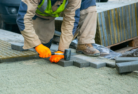 sidewalk, worker laying tiles, work, hammer, pedestrian area, mason laying paving slabs, sidewalk, worker, repair, pedestrian areaの写真素材