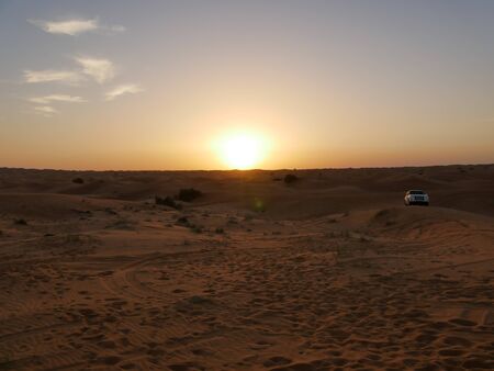 Setting sun on an evening in the desert with safari carの写真素材
