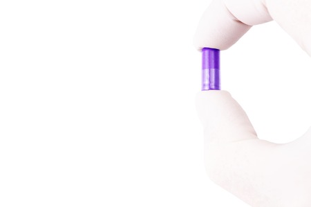 hand in medical glove holding proton purple color organic med capsule isolated on white background closeupの写真素材