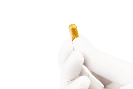 hand in medical glove holding organic med capsule isolated on white background closeupの写真素材