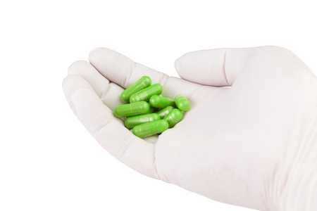 hand in medical glove holding ufo green color organic med capsules isolated on white background closeupの写真素材