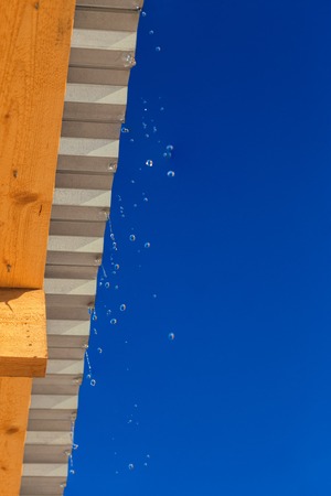 spring water drops flying from edge of barn roofの写真素材