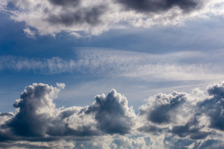 distant misty backlit cumulus and feather clouds near horizon closeup telephoto shot with polarizing effect.の写真素材