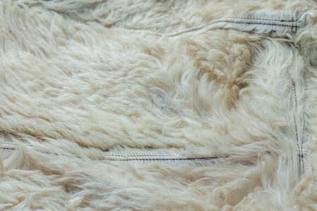Old white sheep fur lining closeup background with selective focus and blur.