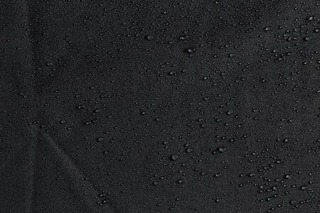 dark gray waterproof hydrophobic flat cloth closeup with rain drops background