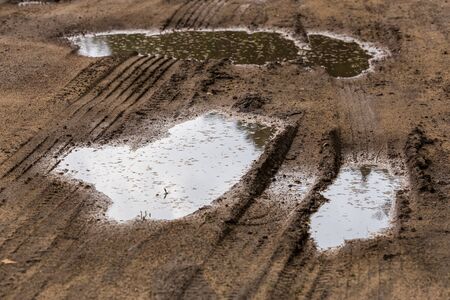puddles in roadside dirt telephoto closeup shot with selective focus and blurの写真素材