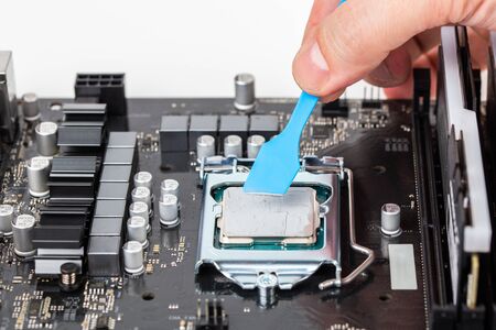 hand applies gray thermal grease on central processor unit in pc motherboard - closeup with selective focusの写真素材