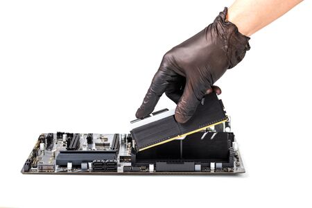 hand in black glove installing memory module with heatsink in pc motherboard isolated on white...