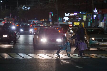 TULA, RUSSIA - OCTOBER 16, 2018: two women with child carriage crossing central prospect at night in light of trafficのeditorial素材