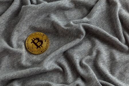 Golden bitcoin shiner on gray crumpled cotton cloth.の写真素材