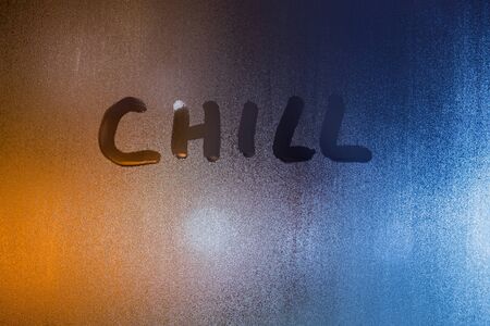 the word chill - written by finger on wet glass with blurred lights in backgroundの写真素材