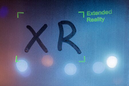 the word xr handwritten by finger on wet window glass with green overlay with words extended reality and corner frame.の写真素材