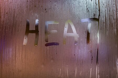 the word heat written on night wet window glass close-up with bokeh backgroundの写真素材