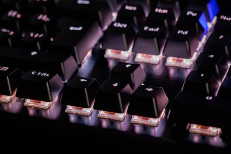 a close-up view of black mechanical pc keyboard with white backlightの写真素材