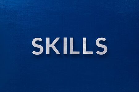 the word skills laid with silver metal letters on classic blue board in flat lay with central composition.の写真素材
