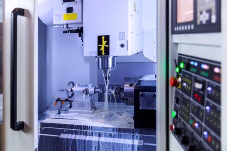 A modern 4-axis cnc vertical milling machine working with water cooling, selective focus on backgroundの写真素材
