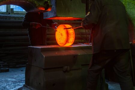close-up picture of hot steel manual forging process with big mechanical hammer machine, sparks flying out from workpieceの写真素材
