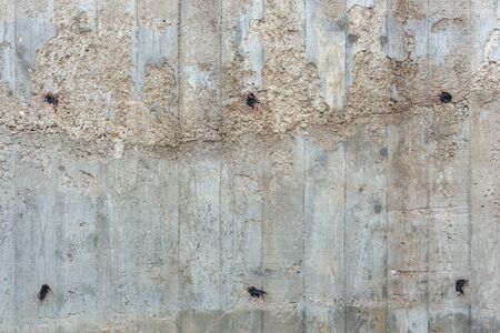 an outdoor thick rough gray concrete wall with visible imprints of wooden planks