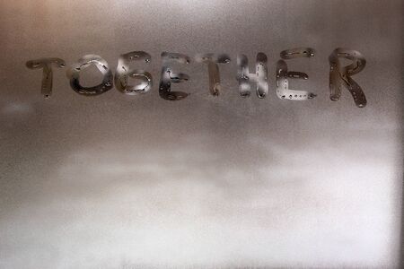 the word together handwritten on wet window glass at daytime - close-up full frame picture with...