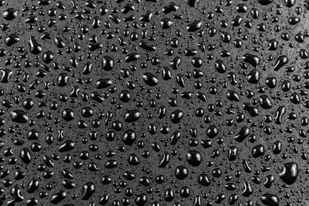 close-up view of water drops on black flat matte surface macro sith selective cous and background blurの写真素材