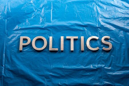 the word politics laid with silver aluminium letters over crumpled plastic blue film background - in center of picture.の写真素材