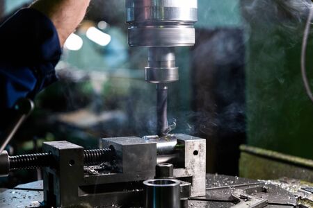 Industrial steel drilling process with smoke close-up with selective focus. Manual feed by hand....