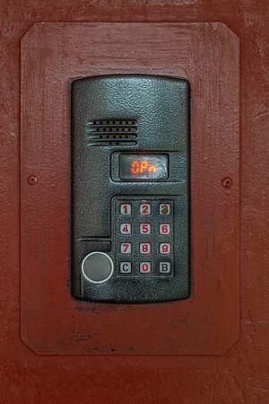 an intercom on old painted brown steel surface with a keypad, digital display and rfid sensor for...