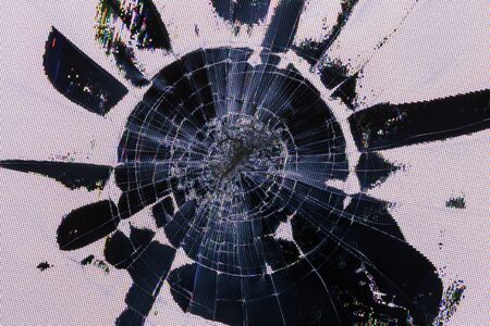 Impact damage on lcd screen, radial cracks, pixel grid leakage and discoloration. Close-up with...