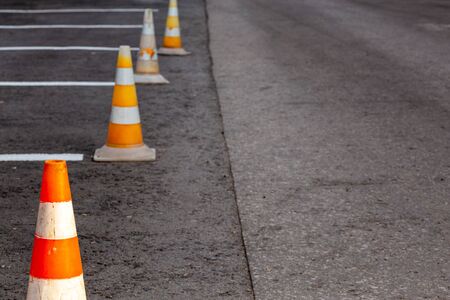 Orange road cones on a asphelt driving area with white lines, close-up with selective focus and backgropund blur.の写真素材