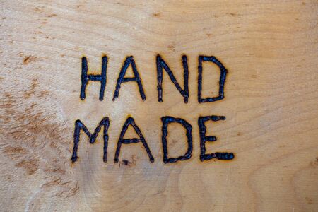 the word hand made handwritten on flat wooden background with electrical woodburner.の写真素材