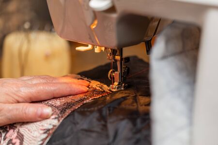 a close-up view of sewing process, hand of old woman using sewing machine, selective focus...